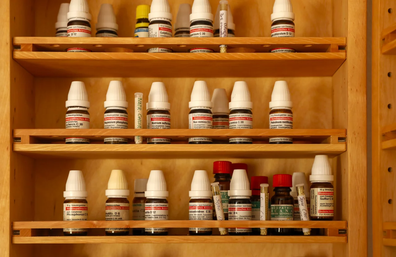 Homöopathische Arzneimittel und Tinkturen zur Beratung sind in der Praxis übersichtlich in einem Holzschrank vorhanden.