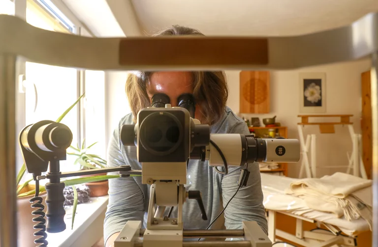Christine Cieslak schaut durch das Augenmikroskop in die Augen der Patienten zur Erstellung der Irisdiagnose.